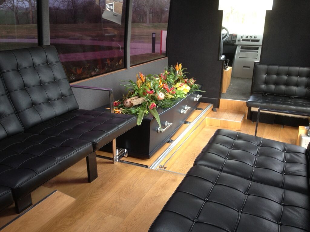 Interieur van de uitvaartbus met lederen banken en een bloemstuk