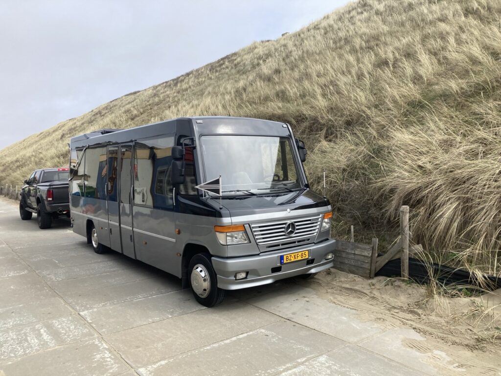 Uitvaartbus langs de duinen met een andere auto erachter